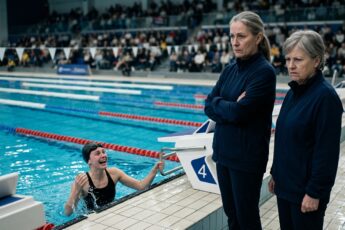 A young swimmer celebrates a win while two rivals watch coldly